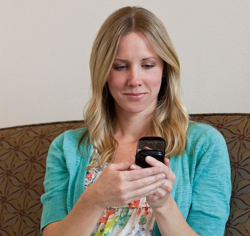 woman sitting on sofa looking at phone