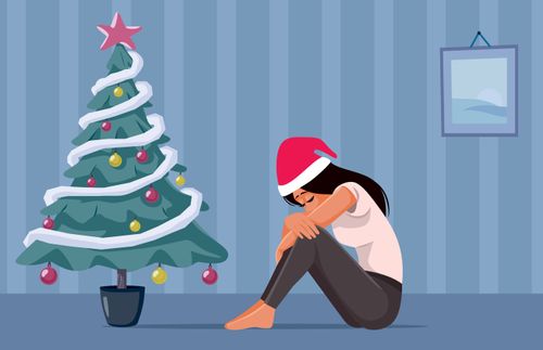 a sad woman sitting under a Christmas tree