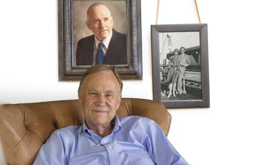 Portrait of Richard A. Hunter sitting in a chair.  There are pictures of his parents in the background.