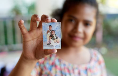 Little girl holding up photo