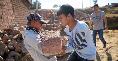 young men lifting mud bricks