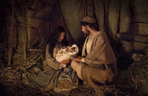 actors portraying Joseph and Mary holding the baby Jesus in a stable