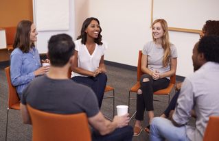 Multi-Cultural Group Of Men And Women At Mental Health Group Therapy Meeting