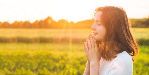 young woman praying in field