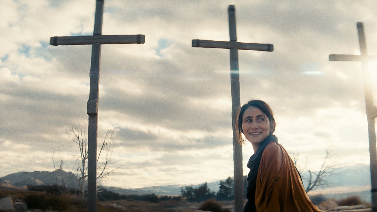 Mujer camina frente a tres cruces