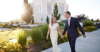 a young couple holds hands outside the temple