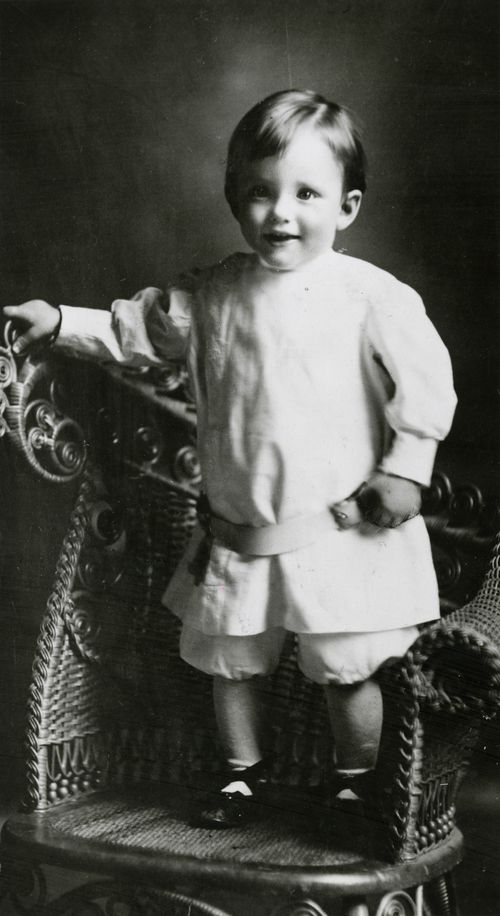 A black-and-white photograph of President Howard W. Hunter smiling and standing on a chair as a young boy.