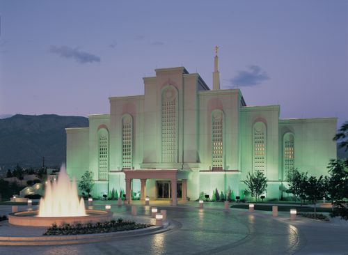 The Albuquerque New Mexico Temple in the late evening, with the lights on the temple grounds illuminating the temple’s exterior.