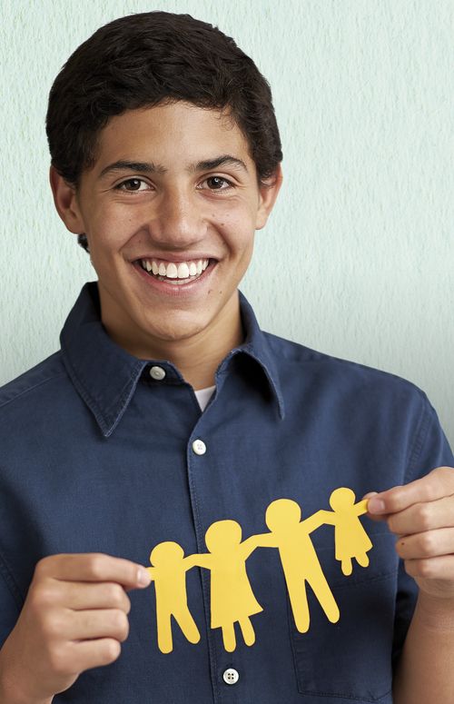 A young man holding up a chain of paper dolls.