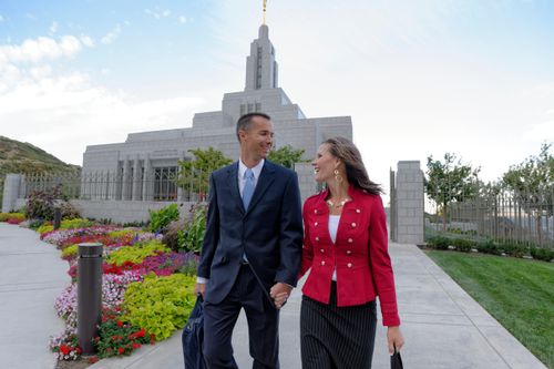 A couple looking at each other and holding hands while walking outside the Draper Utah Temple.