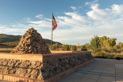 A cairn-style monument on the site of the Mountain Meadows Massacre, with a United States flag nearby.