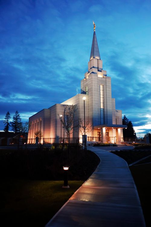 The walkway leading up to the front of the Vancouver British Columbia Temple, with a view of the entire temple lit up at night.