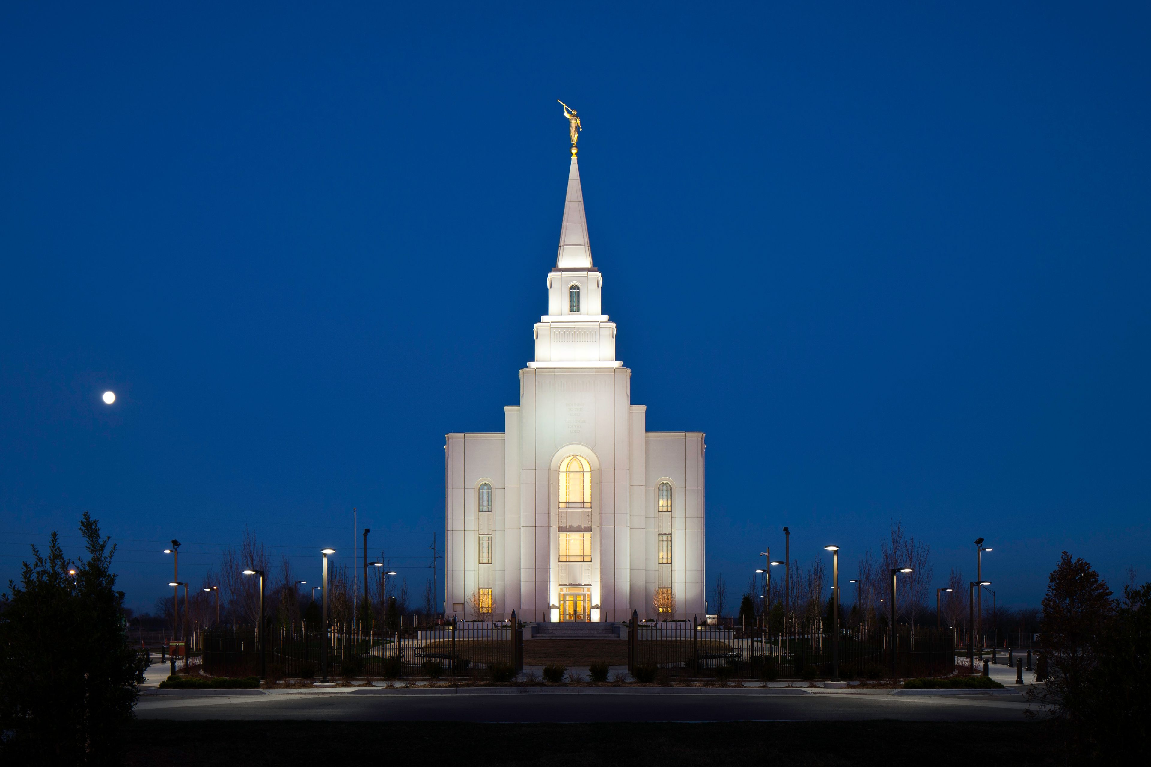 The Kansas City Missouri Temple lit up in the evening, including scenery.  