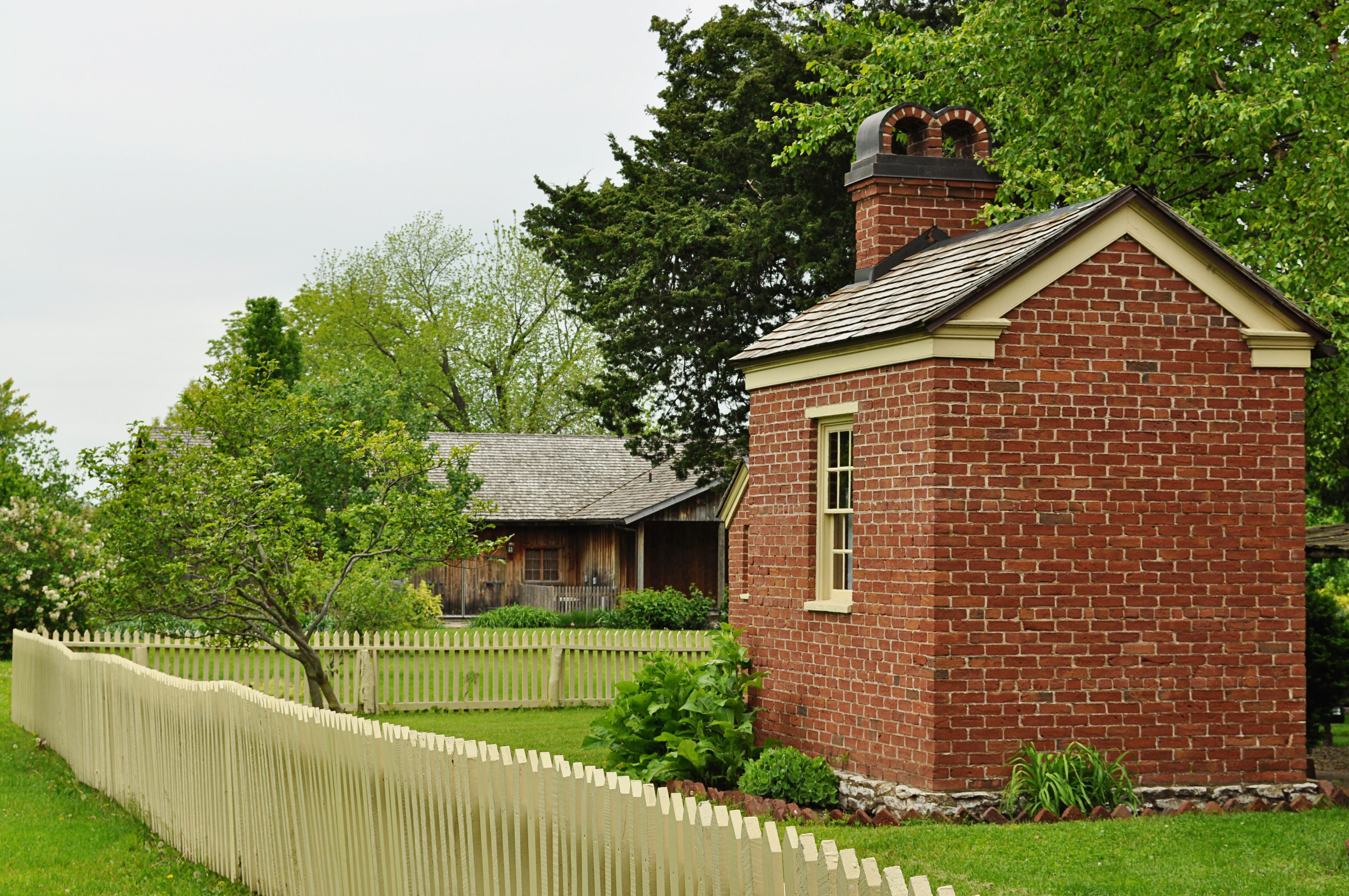 A white picket fence surrounds a red-brick building in Nauvoo.