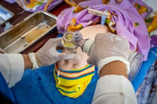 At a birthing center in Indonesia, women are being trained and prepared for birth and caring for their babies. 
A group of midwife's show a group of women how to take care of their children using baby dolls as props. They are teaching them how to use respirators.