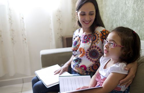 Young family in Brazil read together, parents teach children with drawings, they sing together, mother reading, father holding up chart etc.