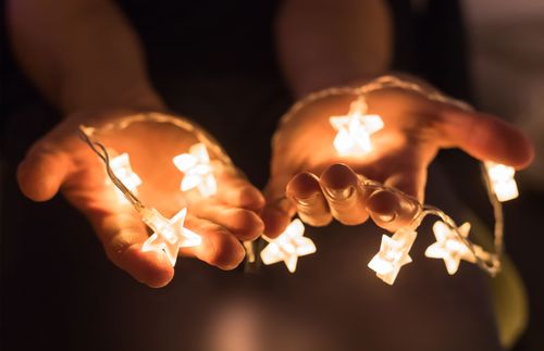 hands holding glowing Christmas lights