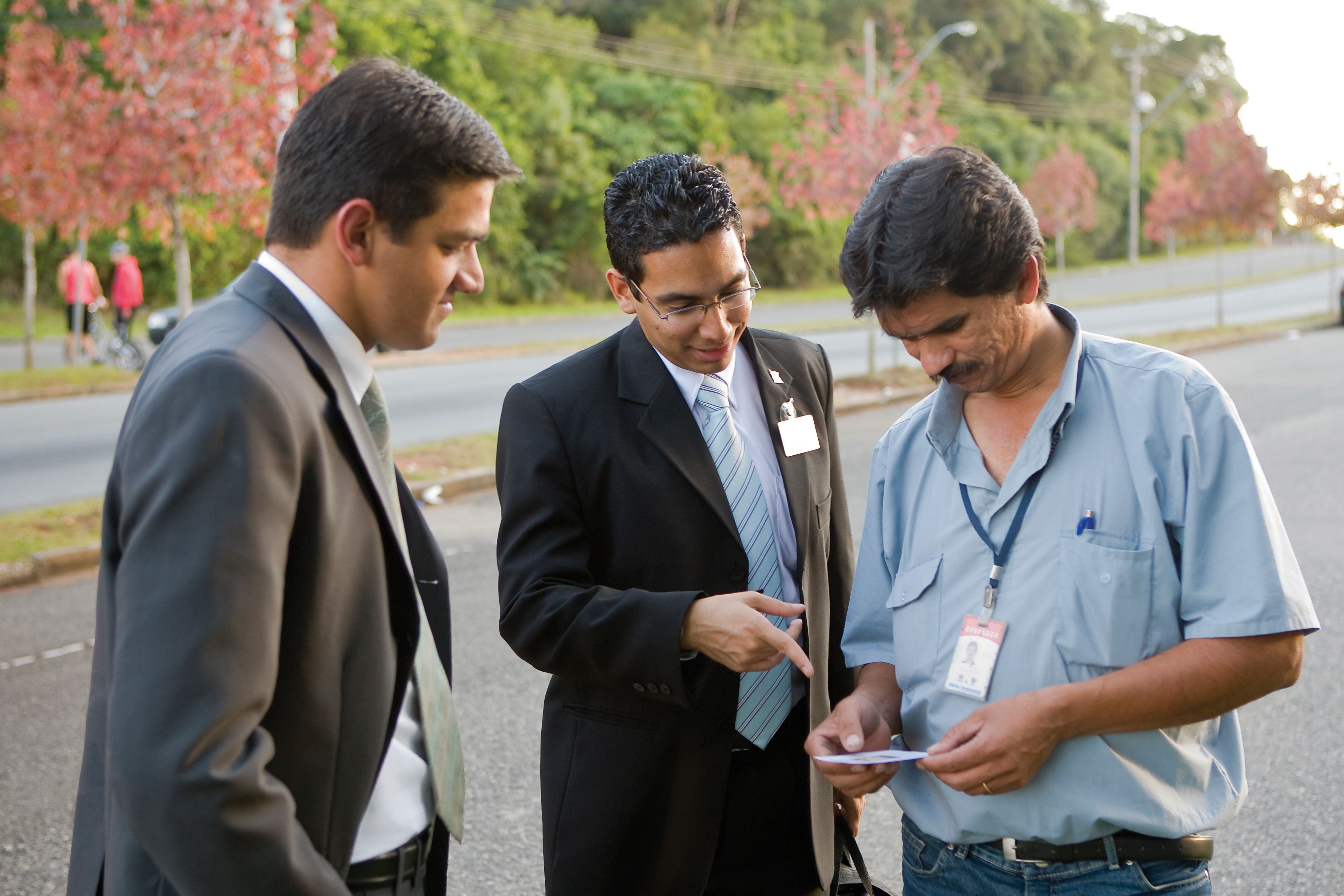 Elder missionaries giving a pass-along card to a man on the street.