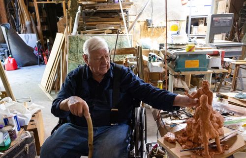 homem em uma cadeira de rodas olhando para uma escultura