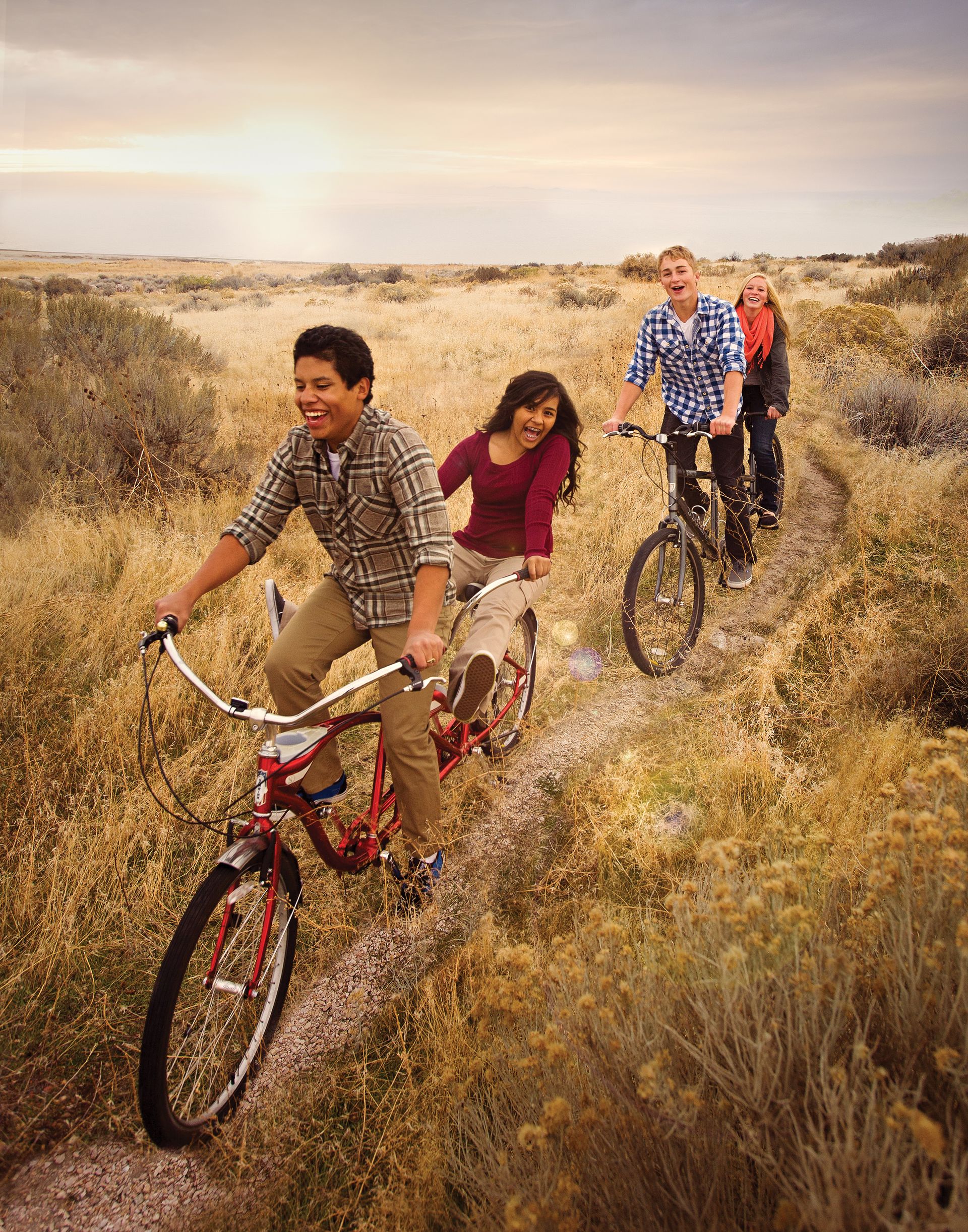 Two couples riding tandem bikes down a narrow path.