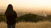 young woman standing on hill looking down on temple in the distance