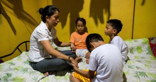 a mother prays with her young children