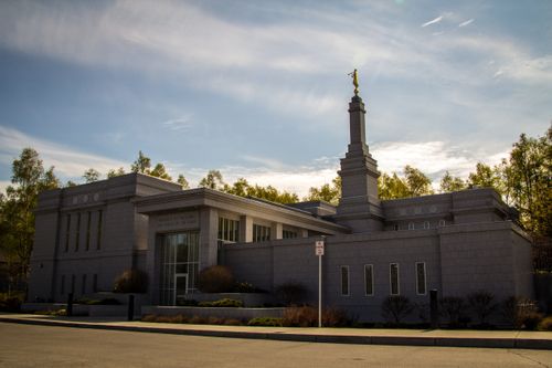 A daytime view of the Anchorage Alaska Temple, with the words “Holiness to the Lord: The House of the Lord” in view above one of the doors.