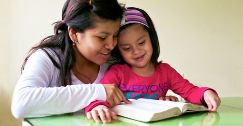 young woman reading with little girl