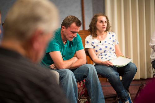 Men and women meeting together in an addiction recovery program.