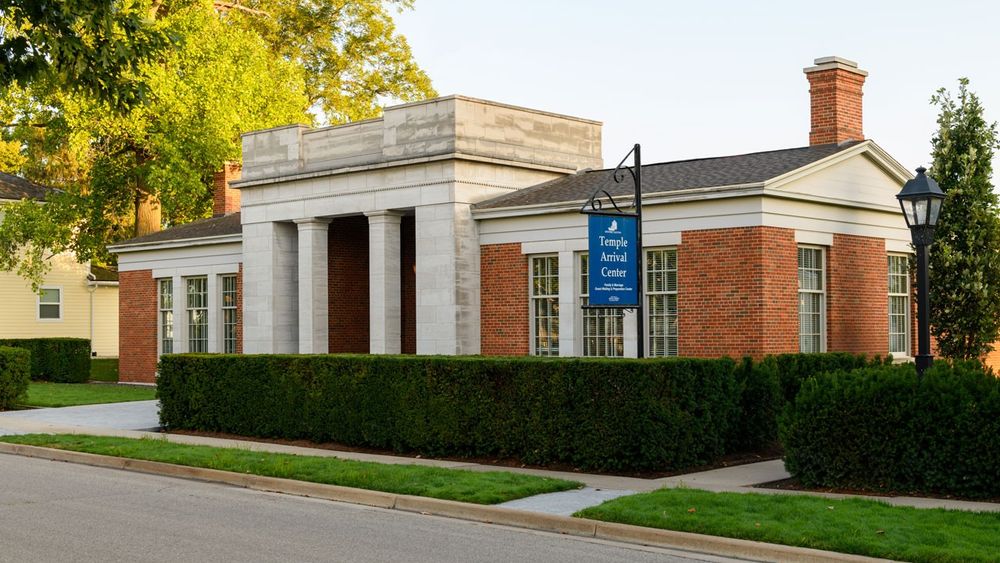 A one-story brick and stone building. There is a blue sign that reads “Temple Arrival Center.”