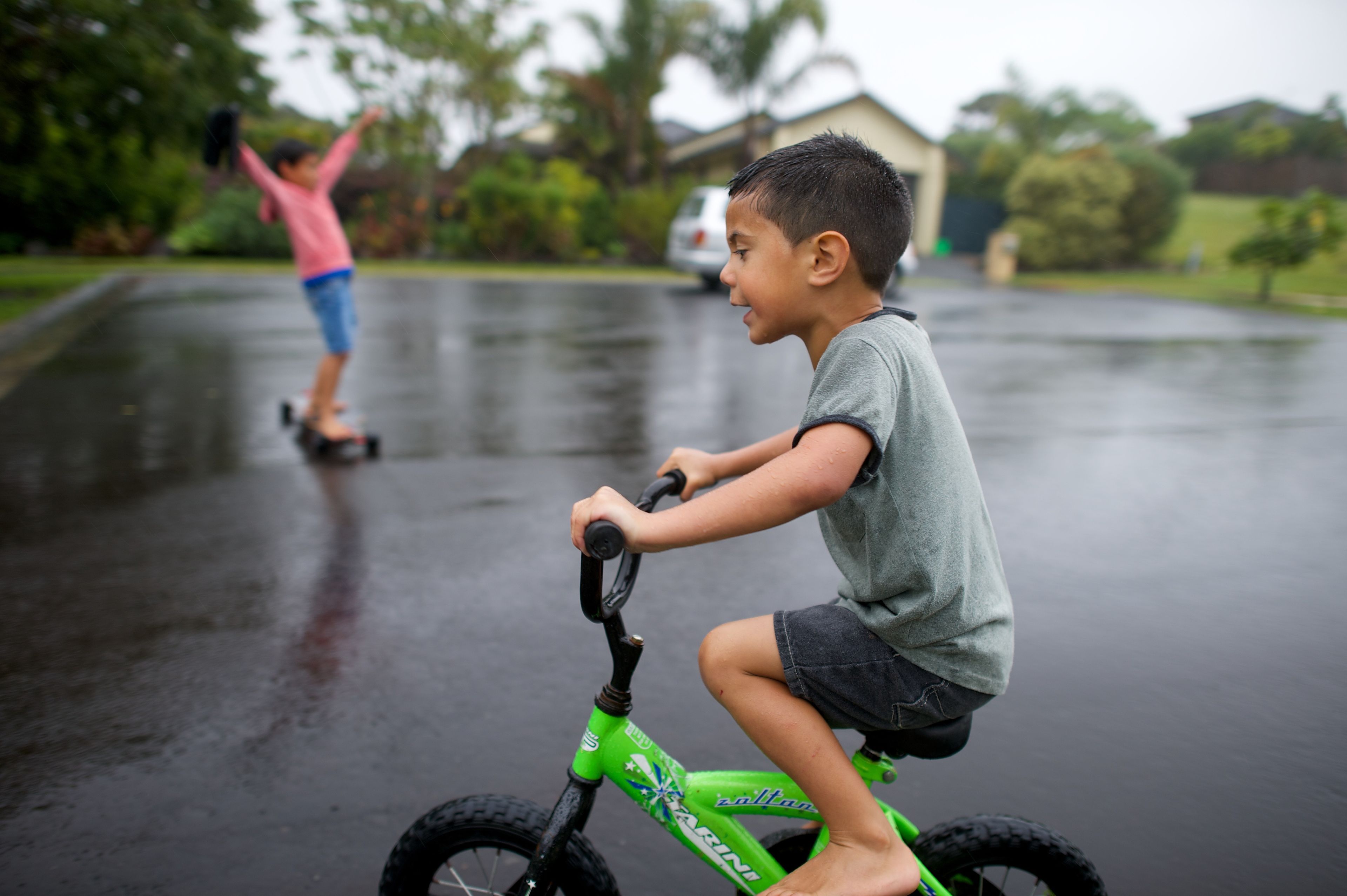 A little boy in New Zealand bikes in the rain