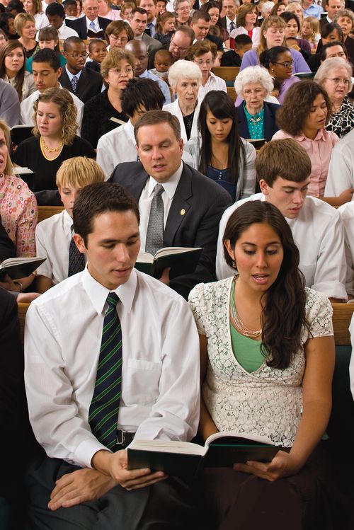 A congregation gathered in a chapel for sacrament meeting.  They are singing a hymn.