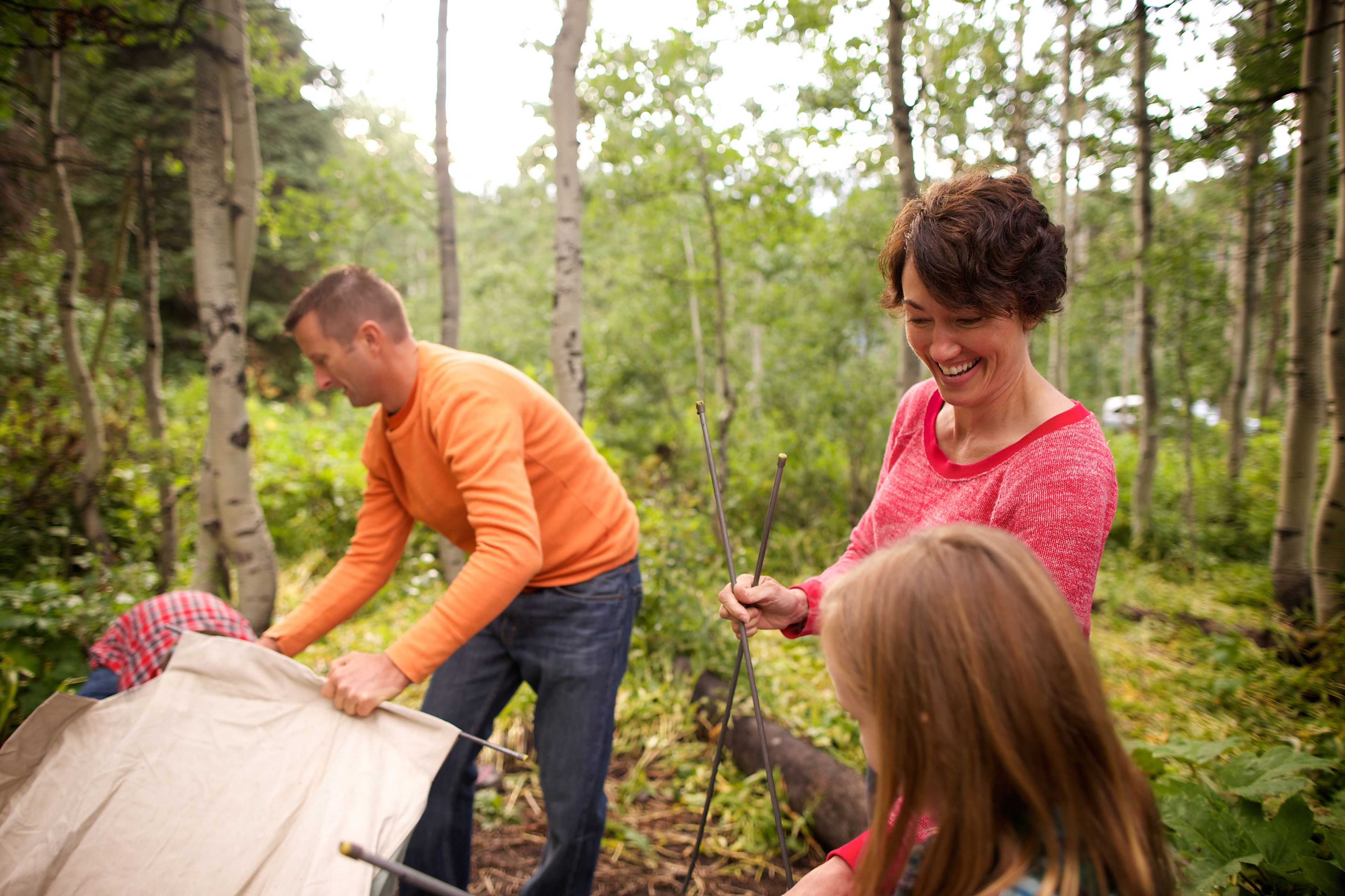 A family setting up a tent as they camp together.