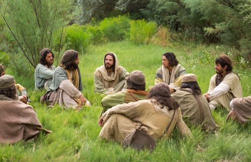 Jesus sitzt im Gras und unterweist seine Jünger
