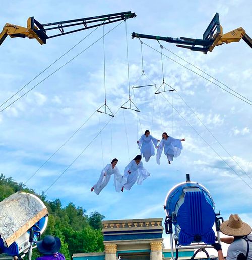 a crane lifting up actors dressed like angels