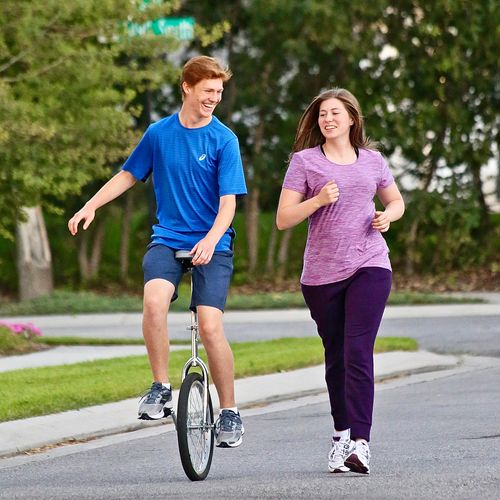 brother on unicycle and sister running