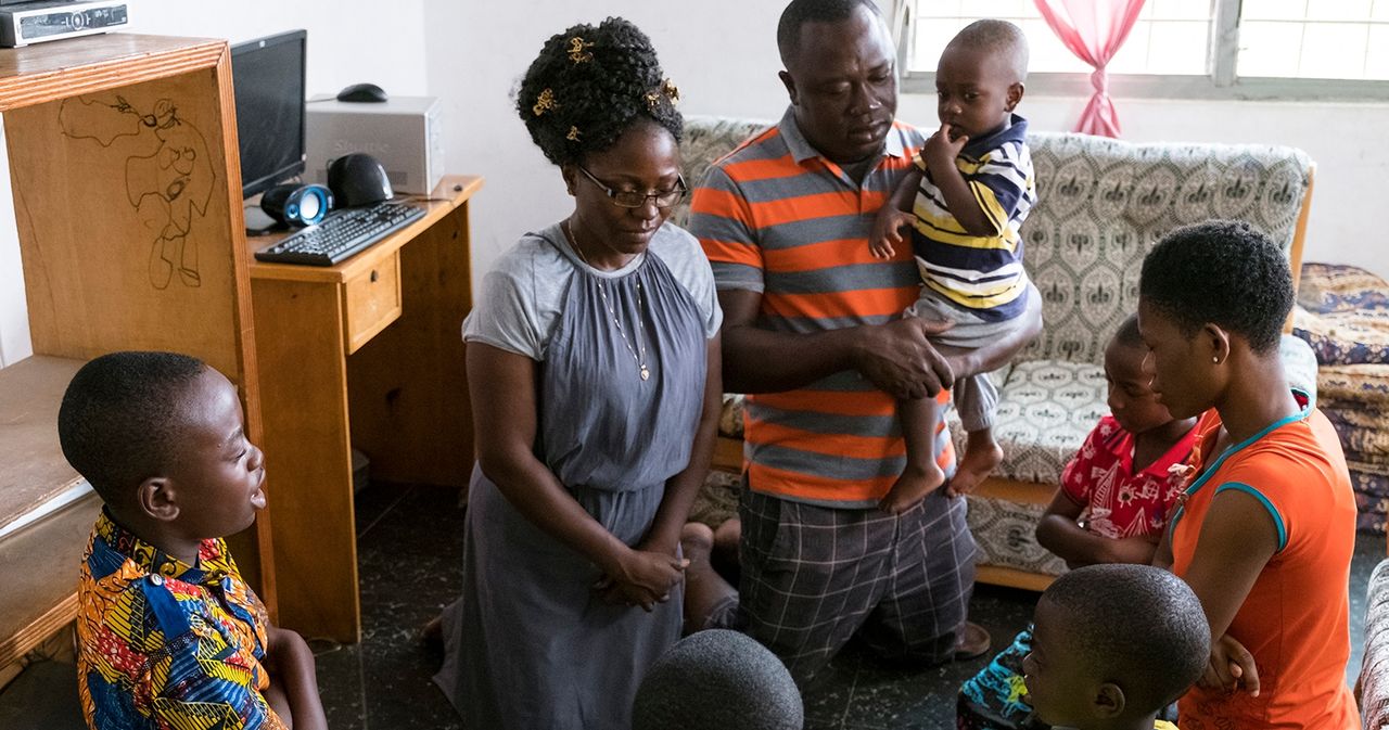 A Ghanan family kneels in the living room to pray together.