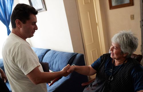 man shaking the hand of an elderly woman