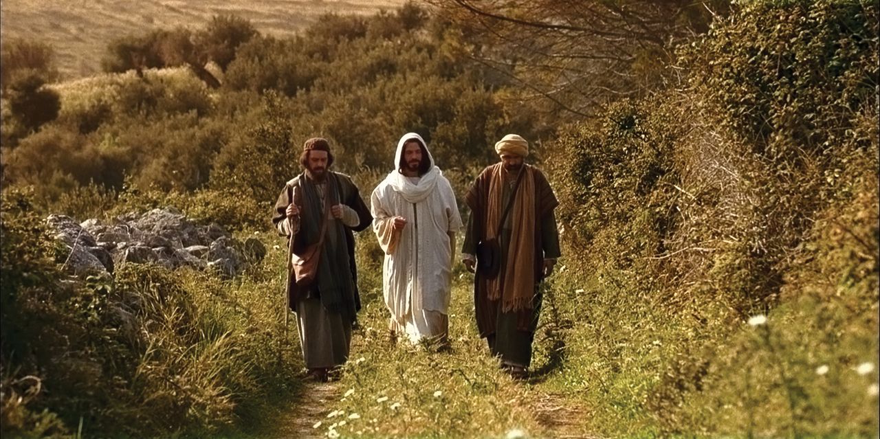 The resurrected Christ walks with two men on the road to Emmaus