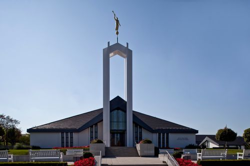 A view of the front of the Freiberg Germany Temple partially in shadow, with a clear blue sky in the background.