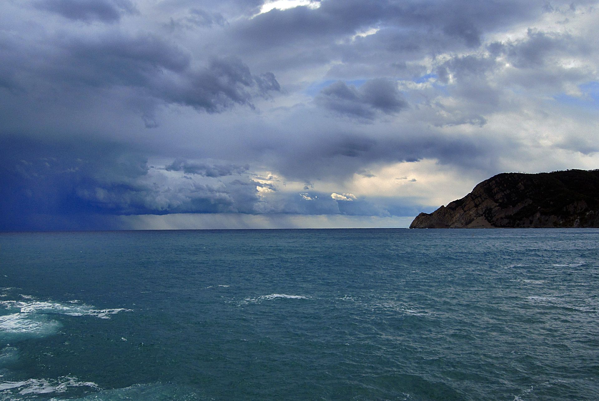 A dark, cloudy sky over the ocean and coast.