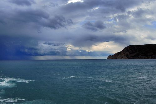 A dark, cloudy sky over the ocean and a rocky coast.