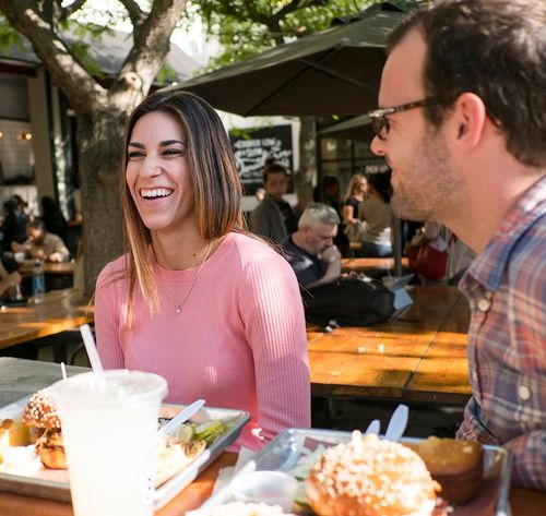 woman and man eating burgers outside