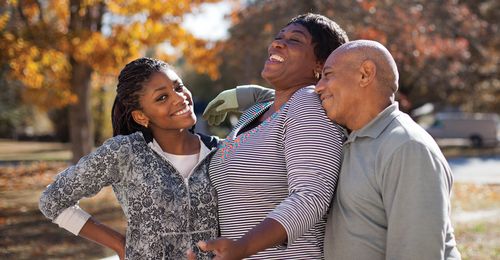 Parents and teenage daughter standing together and laughing.