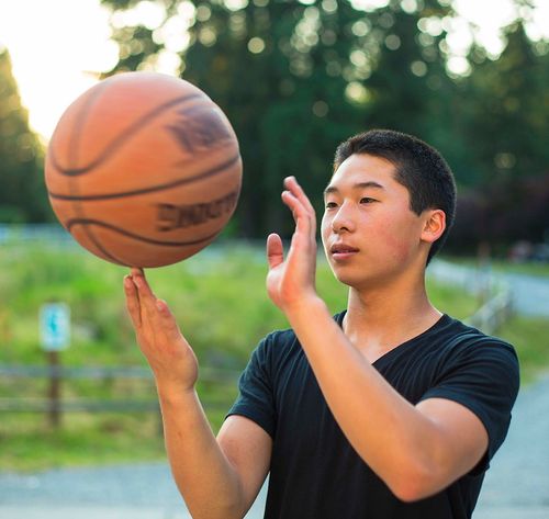 un adolescente haciendo girar una pelota de básquetbol con un dedo