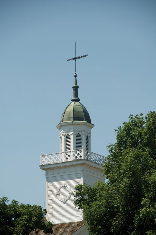 A detail of the spire on the Kirtland Temple, with the green leaves of several trees in view near the bottom of the frame.
