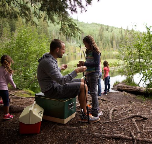 father helping kids set up fishing poles