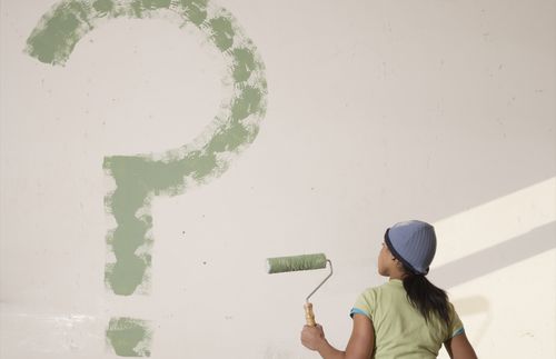 woman painting a question mark on a wall