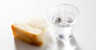 copo do sacramento com água e um pedaço de pão