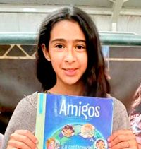 girl holding up Friend magazine in Spanish